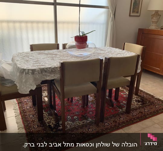 שולחן אוכל עם מפה לבנה ועציץ במרכז